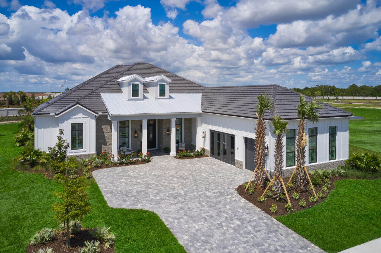 Model home exterior with paver driveway and palms at Waterbury Park, Lakewood Ranch, Florida