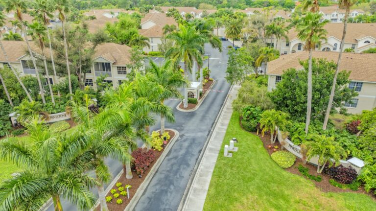 Gated entrance with Pinestone signs and royal palms at Pinestone at Palmer Ranch, Sarasota, Florida