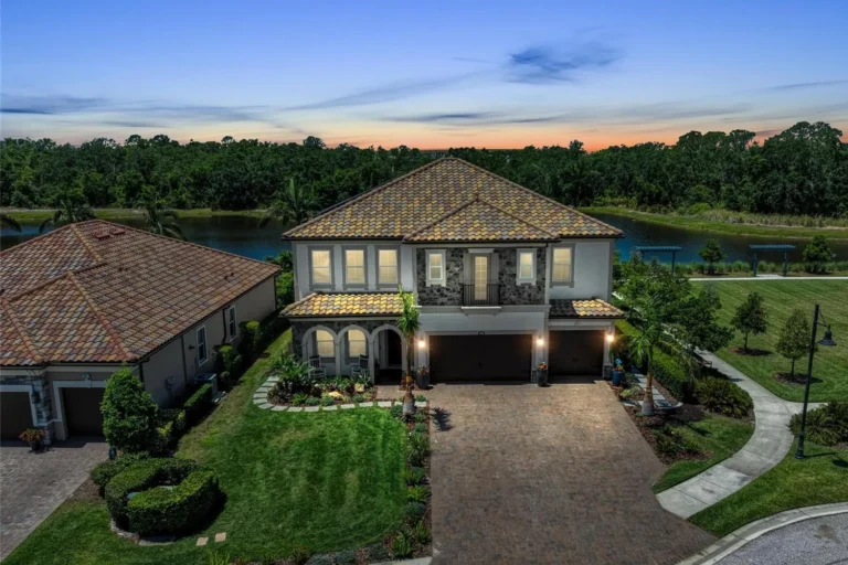 Two-story home with a tile roof at twilight on a lake and preserve in Arbor Grande, Lakewood Ranch