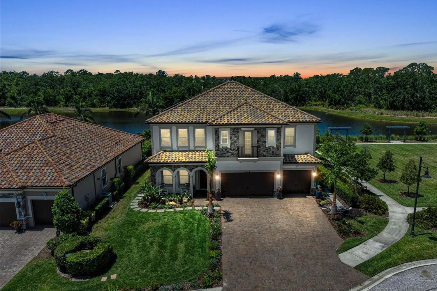 Two-story home with a tile roof at twilight on a lake and preserve in Arbor Grande, Lakewood Ranch